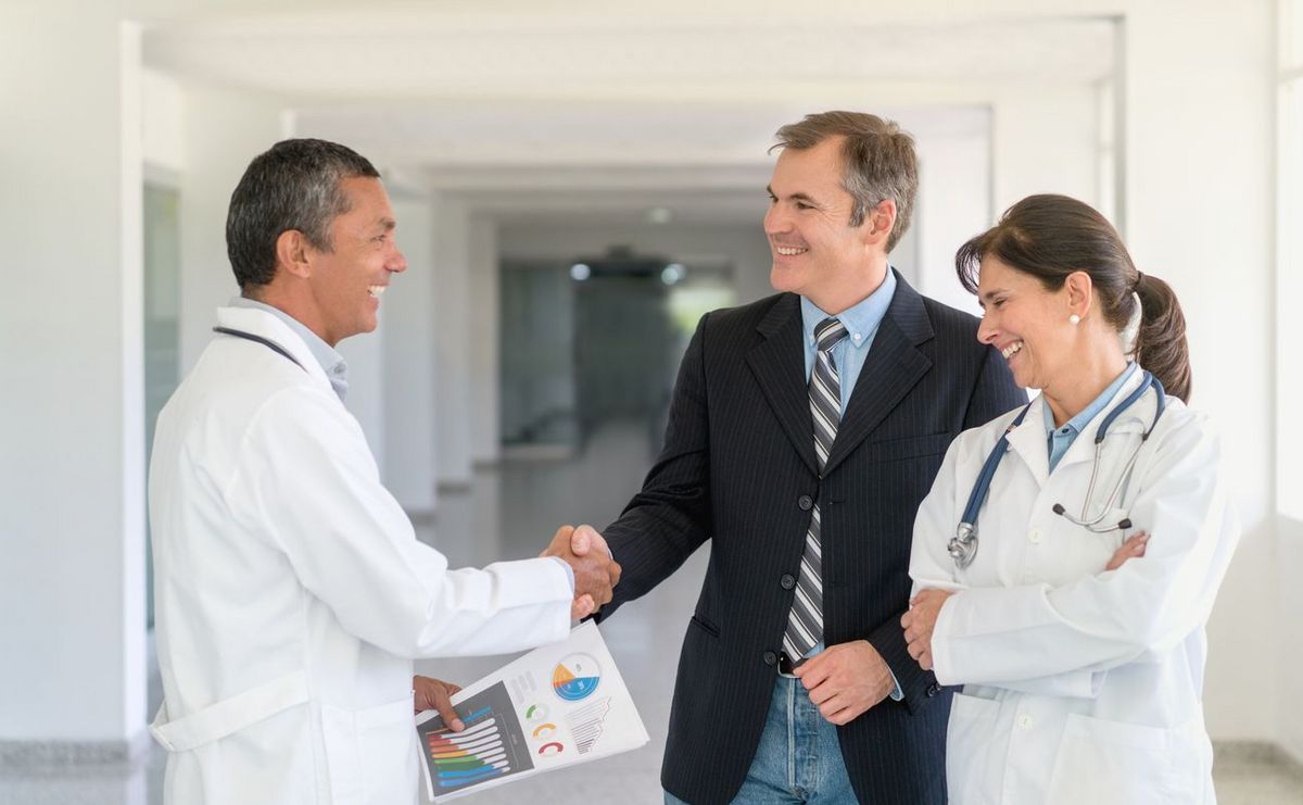 Arzt schüttelt Mann im Anzug die Hand